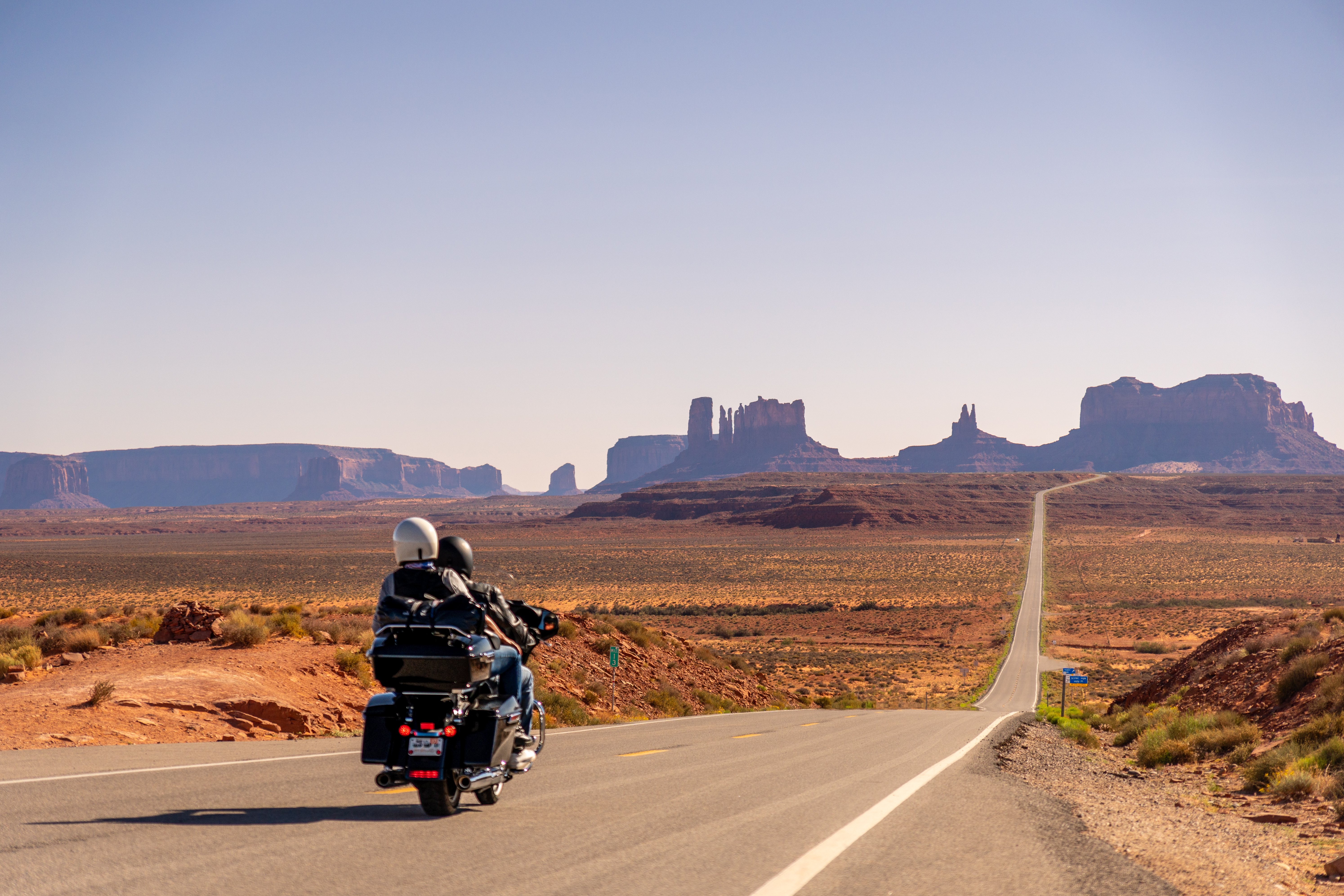 Couple riding a motorcycle on a scenic highway.