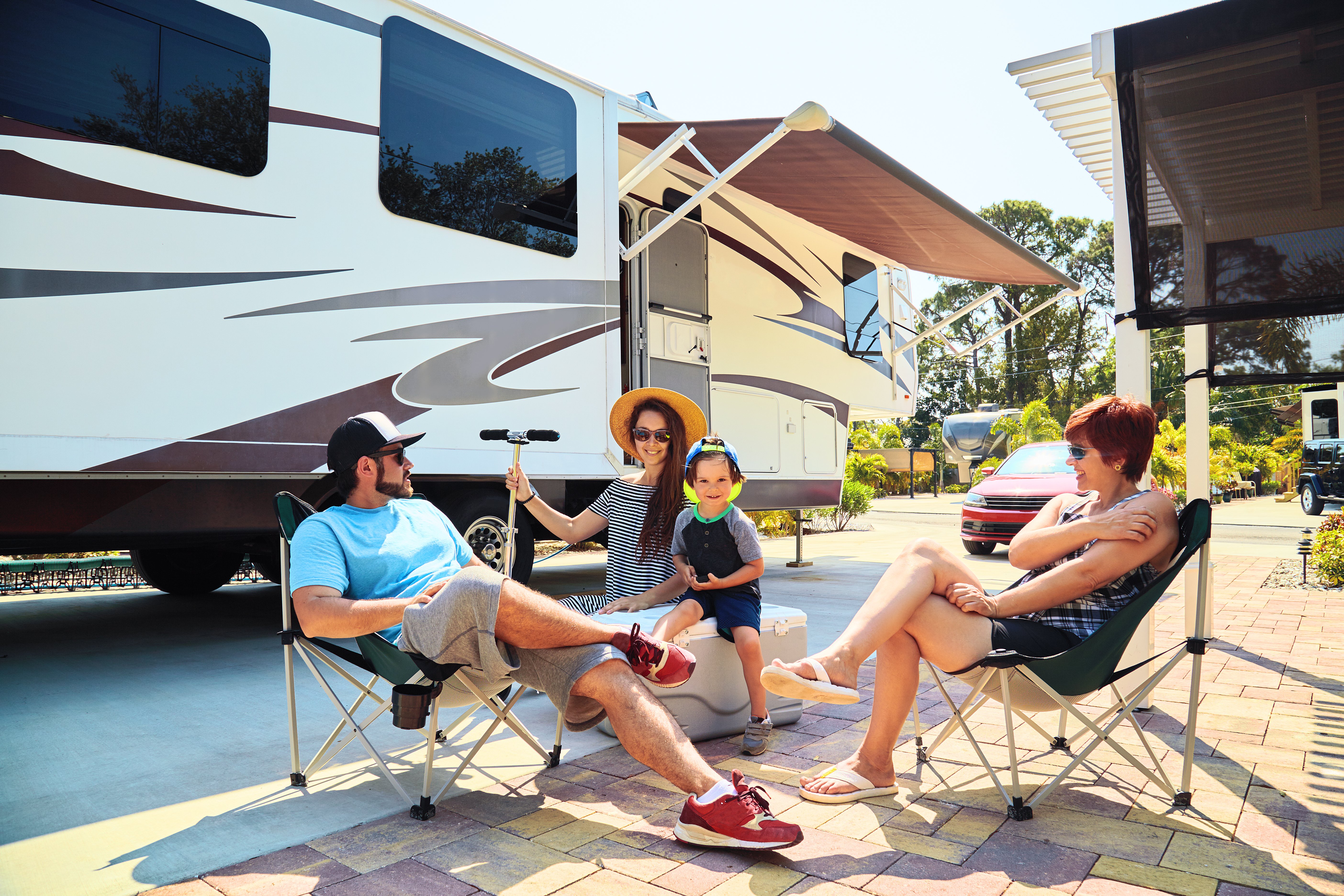 Family sitting in camping chairs outside at an RV park.