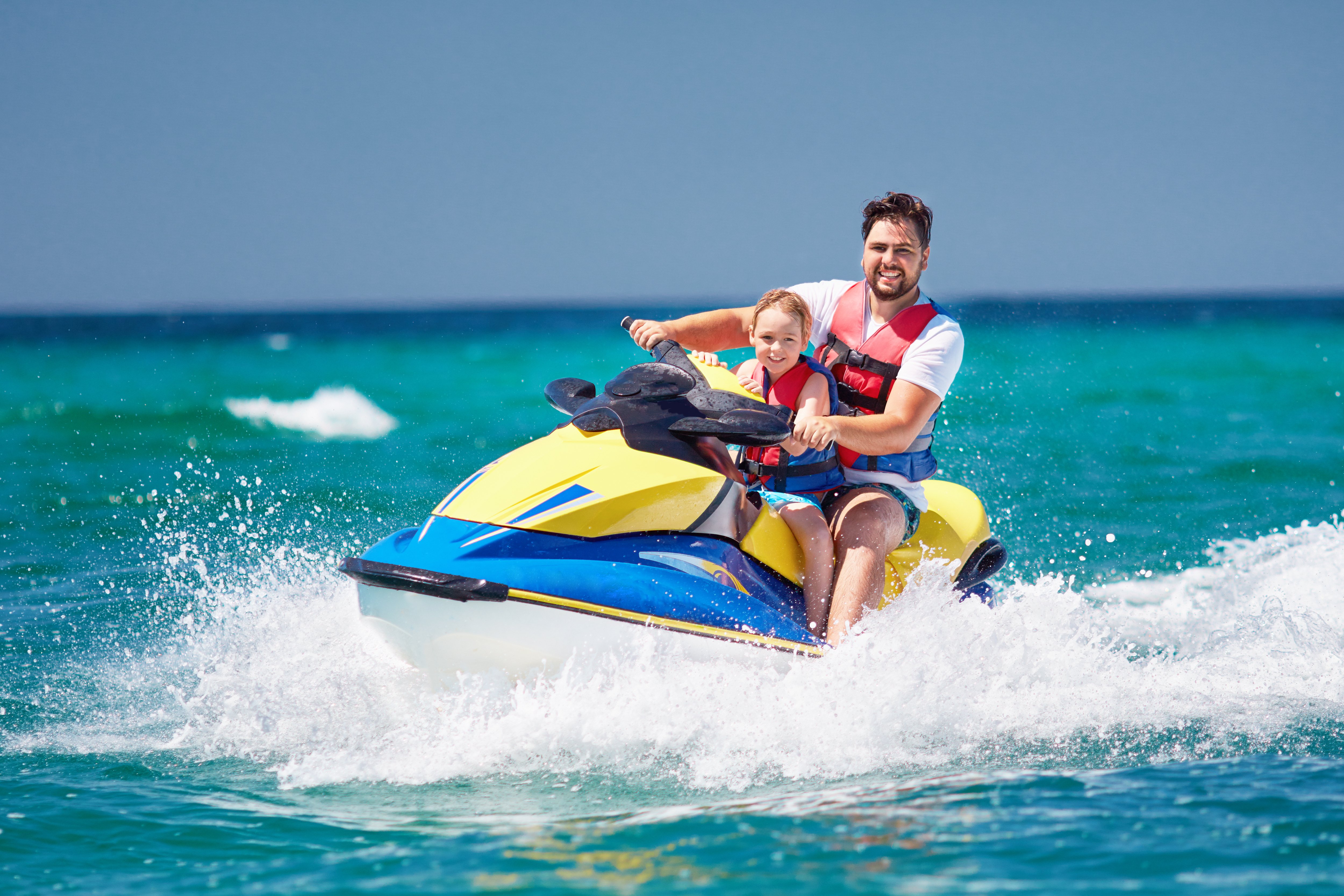 Father and daughter riding a jet ski.