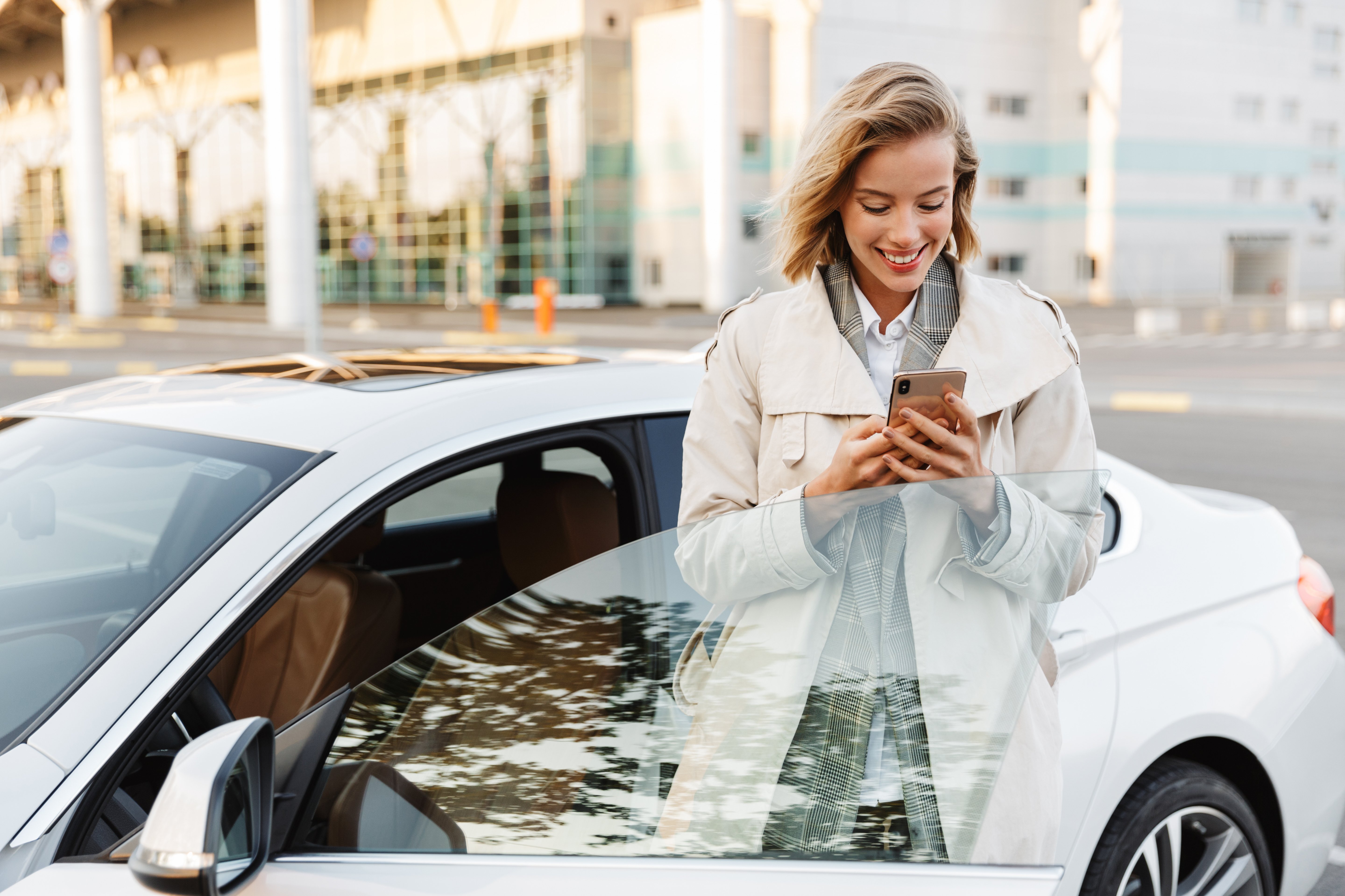 Woman standing by a car using a mobile device.