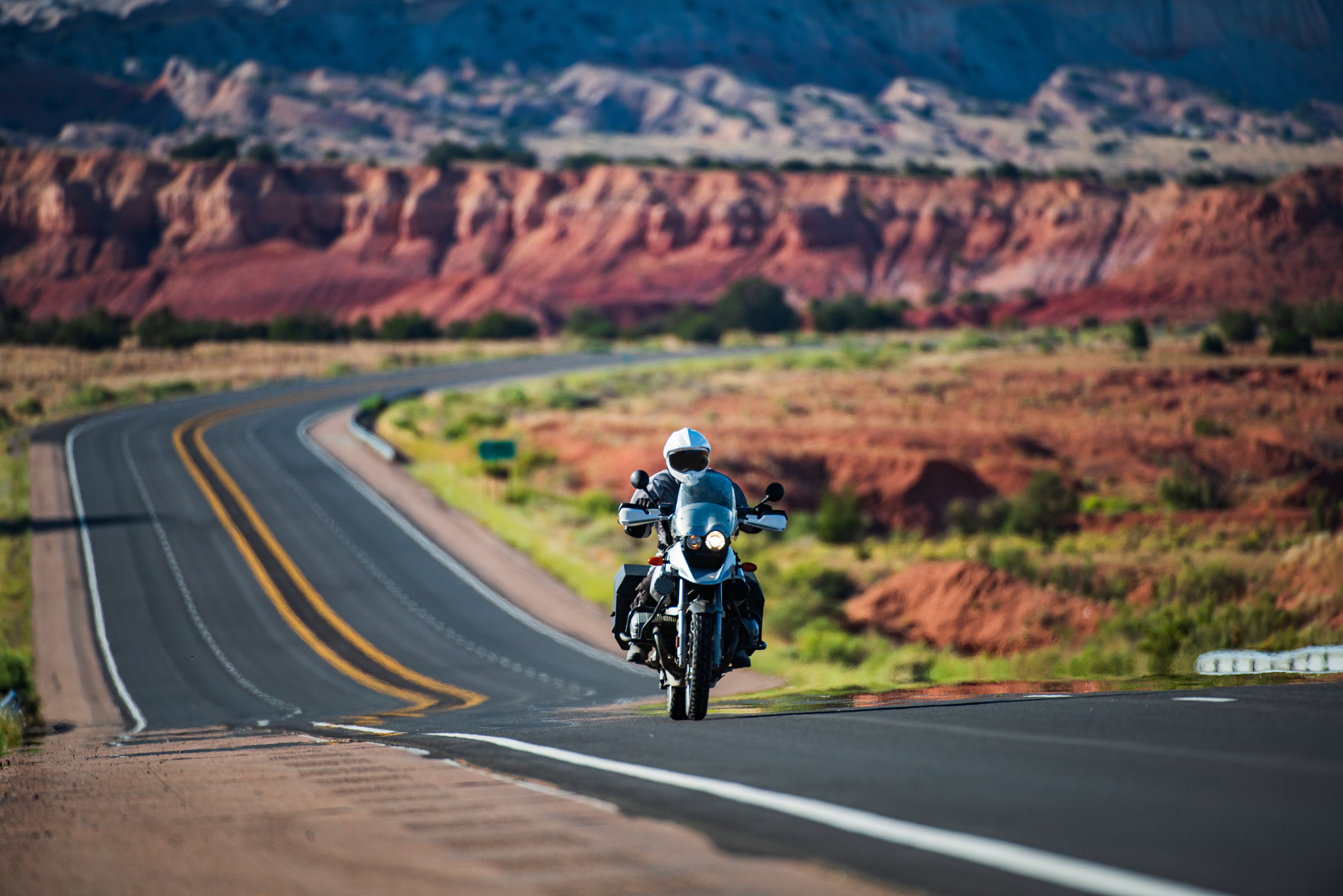 Adventure motorcycle rider cruising down a scenic desert highway, illustrating freedom with a motorcycle loan.