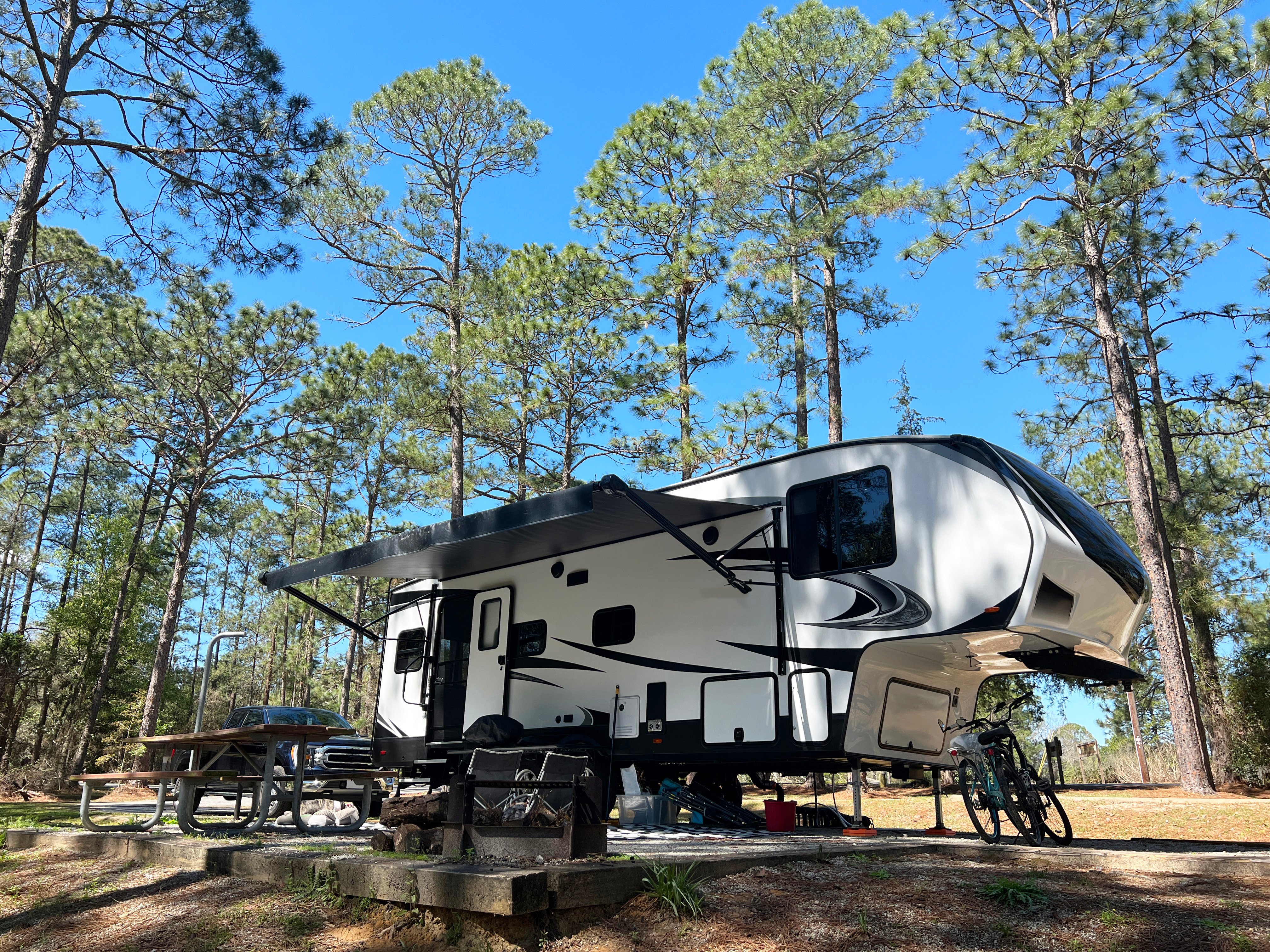 Fifth-wheel RV parked at a wooded campsite.