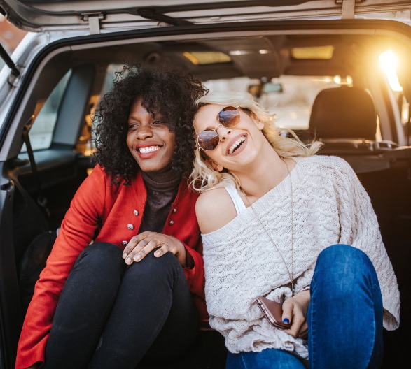 Two friends sitting in a car after getting an Auto Loan.