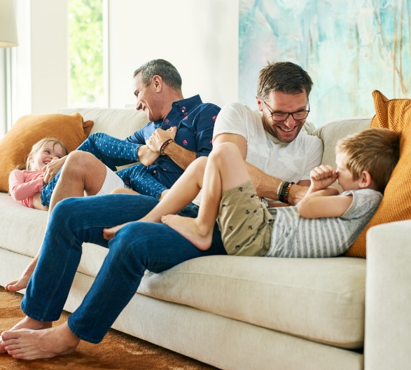 Two fathers on the couch with children after home improvements made with a home equity loan.