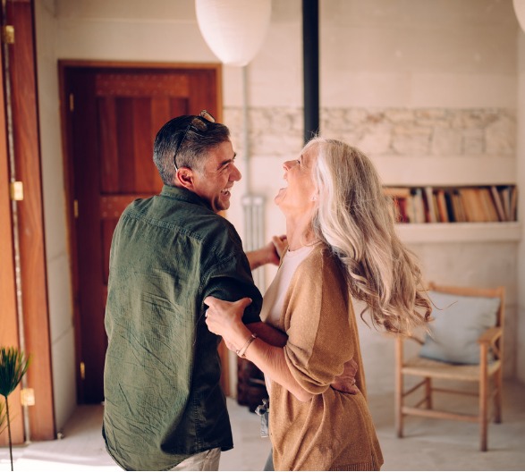 happy-senior-couple-dancing-and-laughing-together-at-home-picture-id996990764