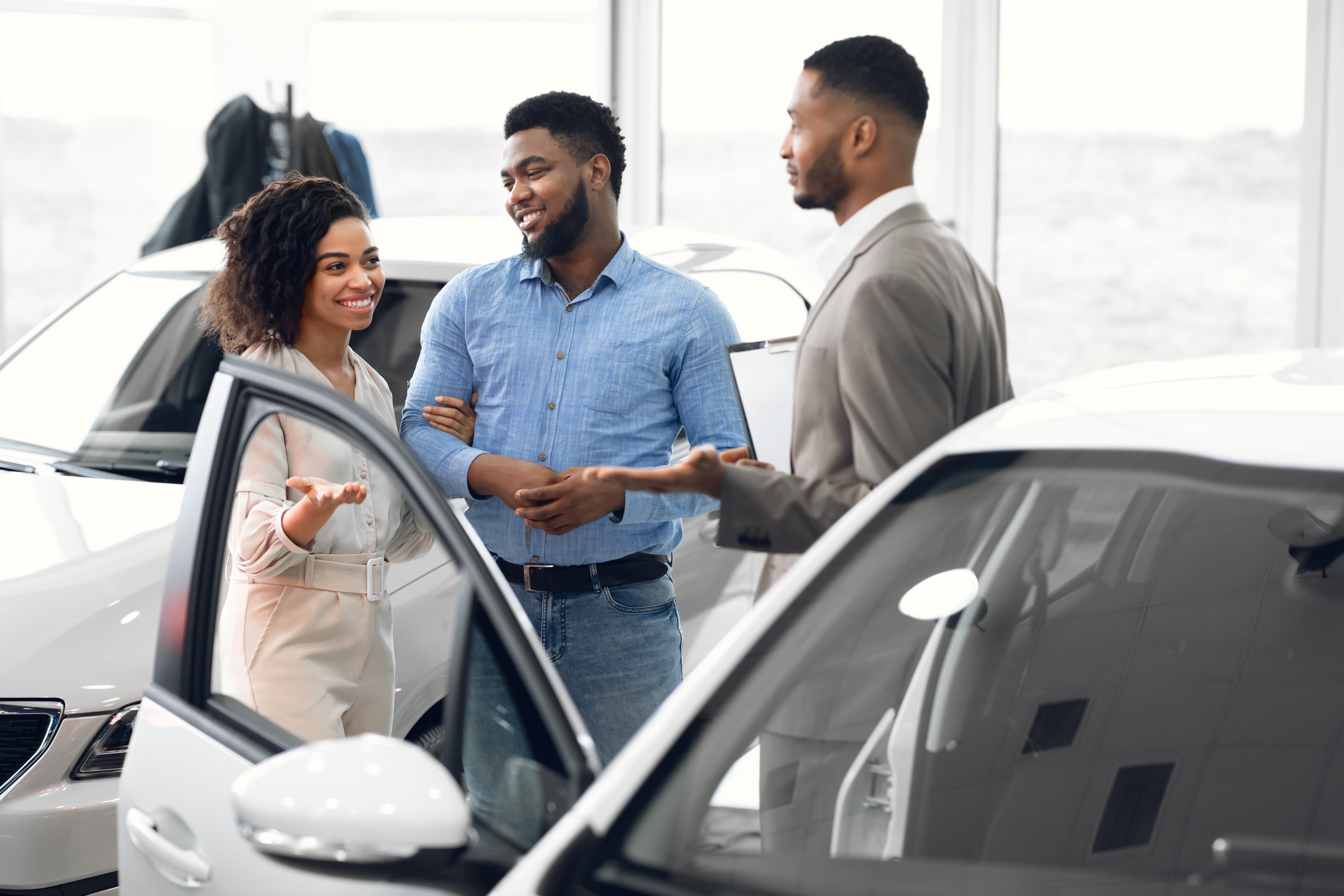 Man and woman talking to car salesman 