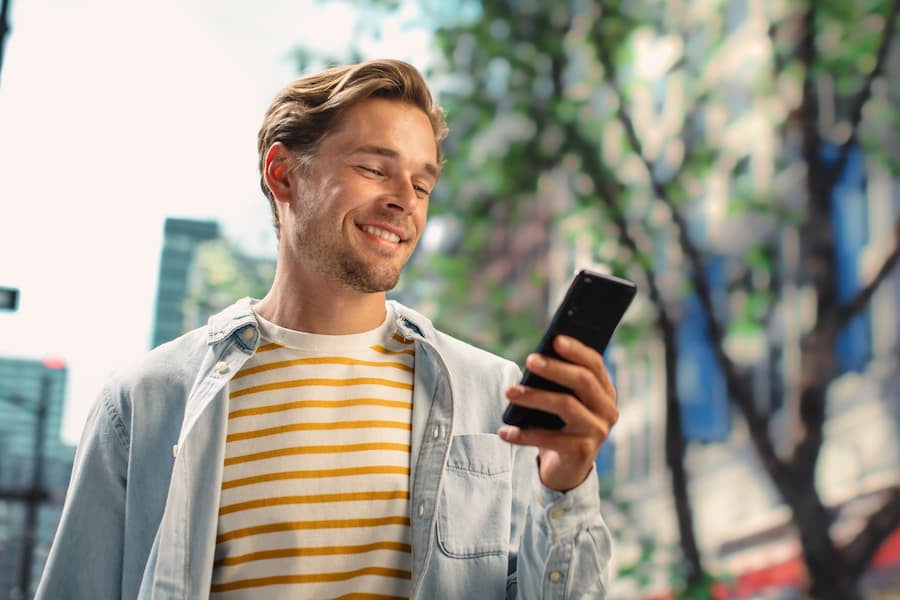 Man smiling as he sees on his phone that his shared secured personal loan was approved.