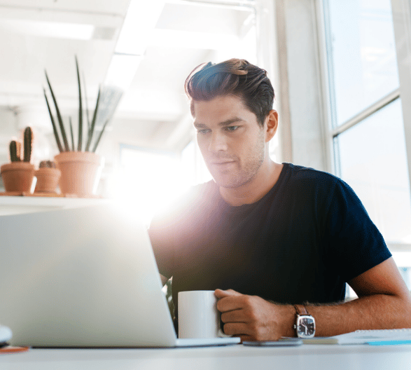 Man Using Computer Holding Coffee