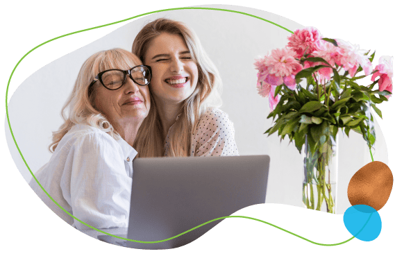 happy grandmother hugging granddaughter on a laptop