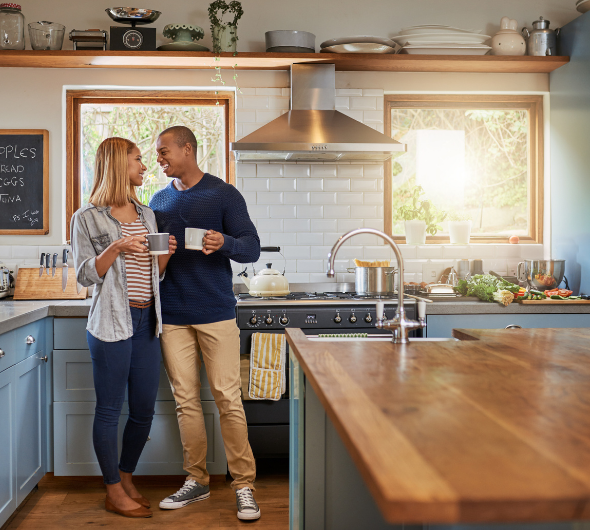 Husband and Wife Standing in Kitchen With Coffee in New House