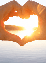 hands forming a heart with sun penetrating