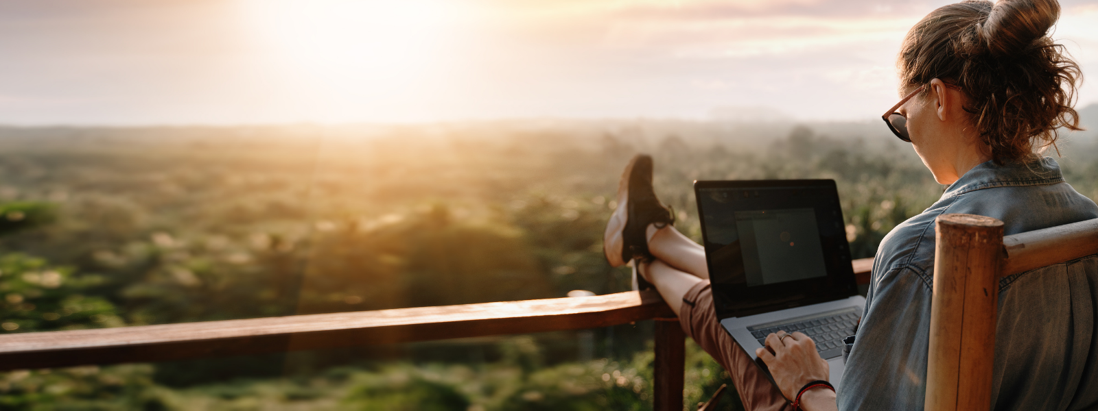 girl sitting on porch on computer during sunset