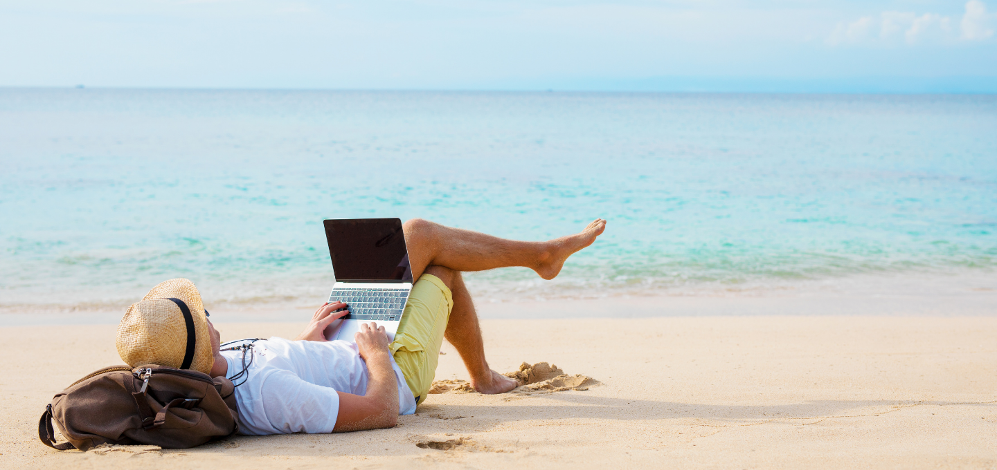 man-lying-on-beach-with-laptop
