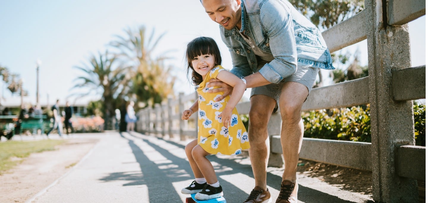 father-helps-young-daughter-ride-skateboard